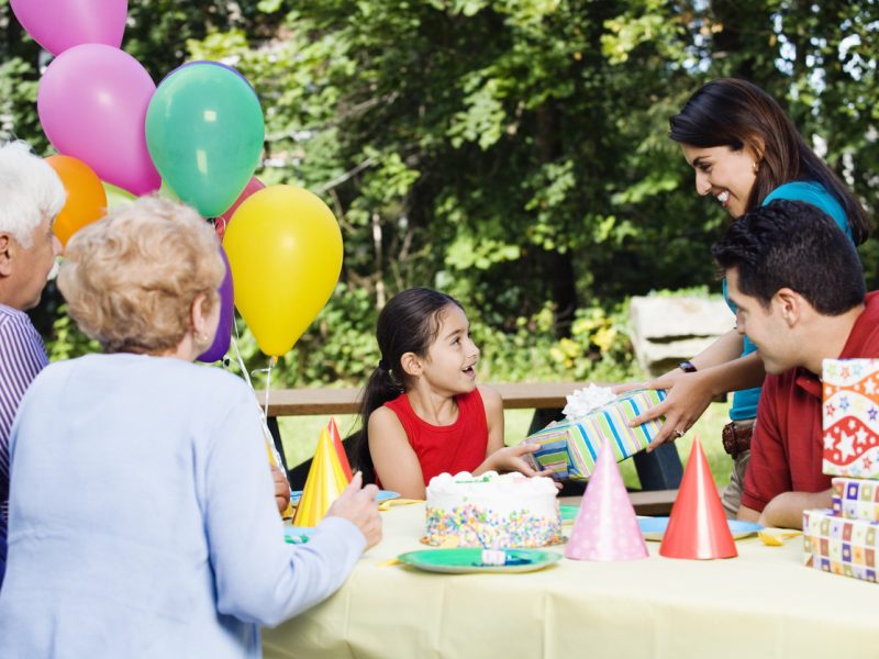 Hispanic girl receiving gifts at birthday party