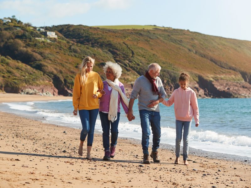 Multi-Generation Family Walking Along Shore On Winter Beach Vacation
